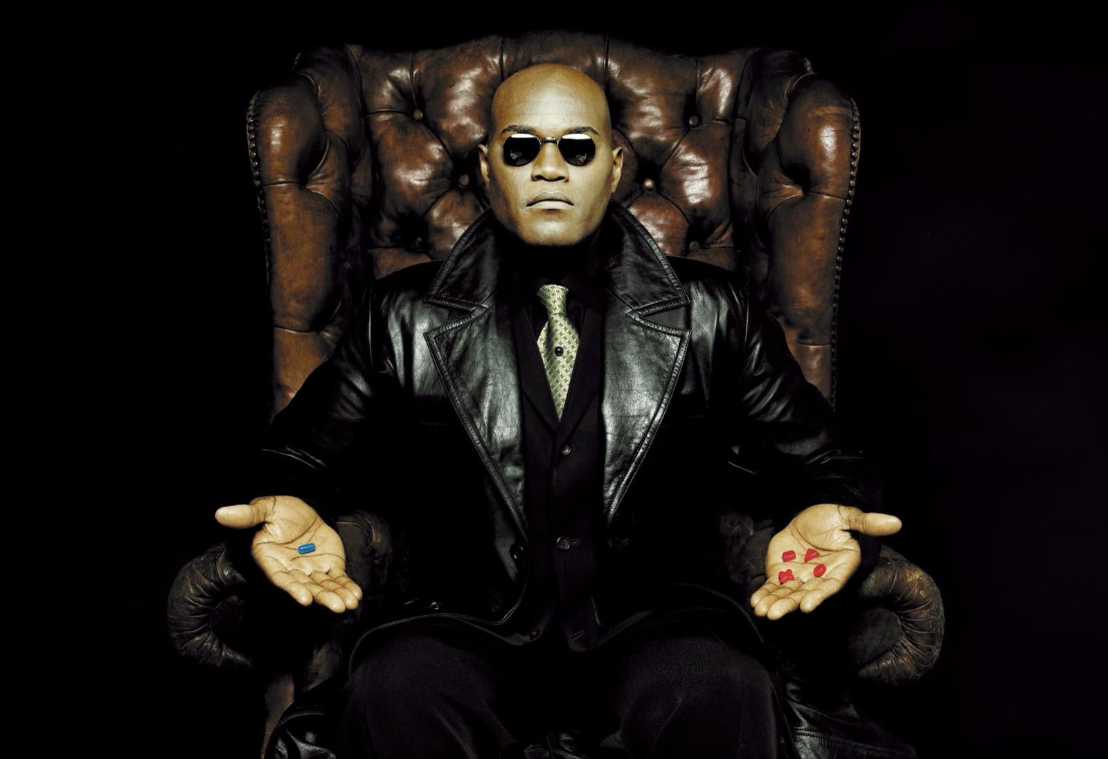 A figure in a leather coat in a chesterfield armchair offering a blue pill and red pills. Dimitri Daniloff
